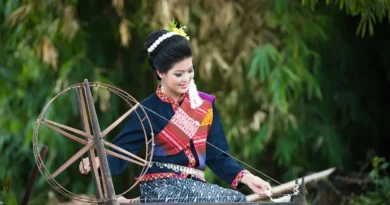 Seorang wanita yang sedang menenun benang menggunakan alat seperti roda